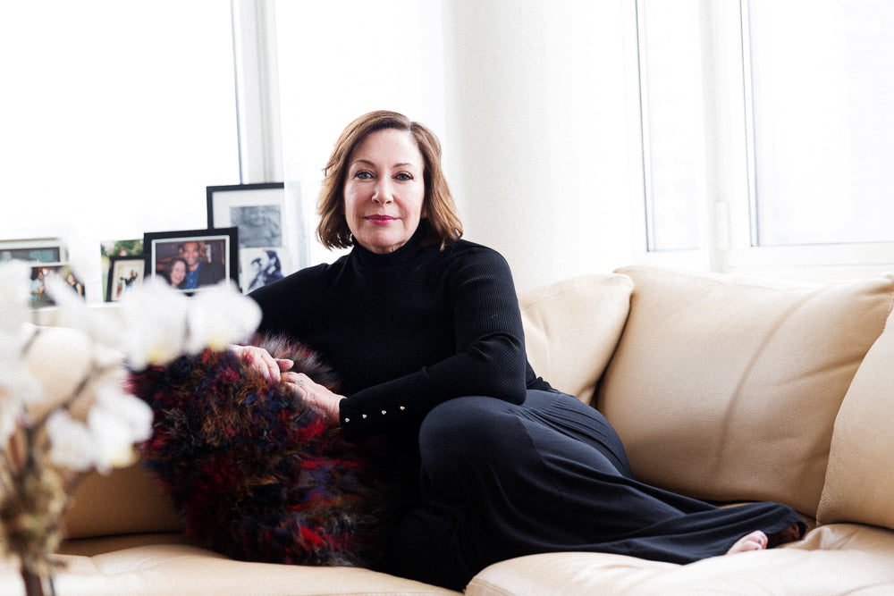 Deborah Lippmann smiling while laying on a couch