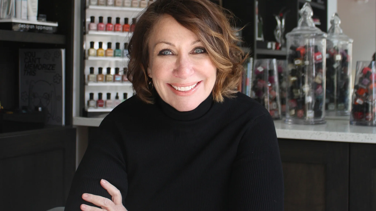 Deborah Lippmann smiling with her nail polish products behind her
